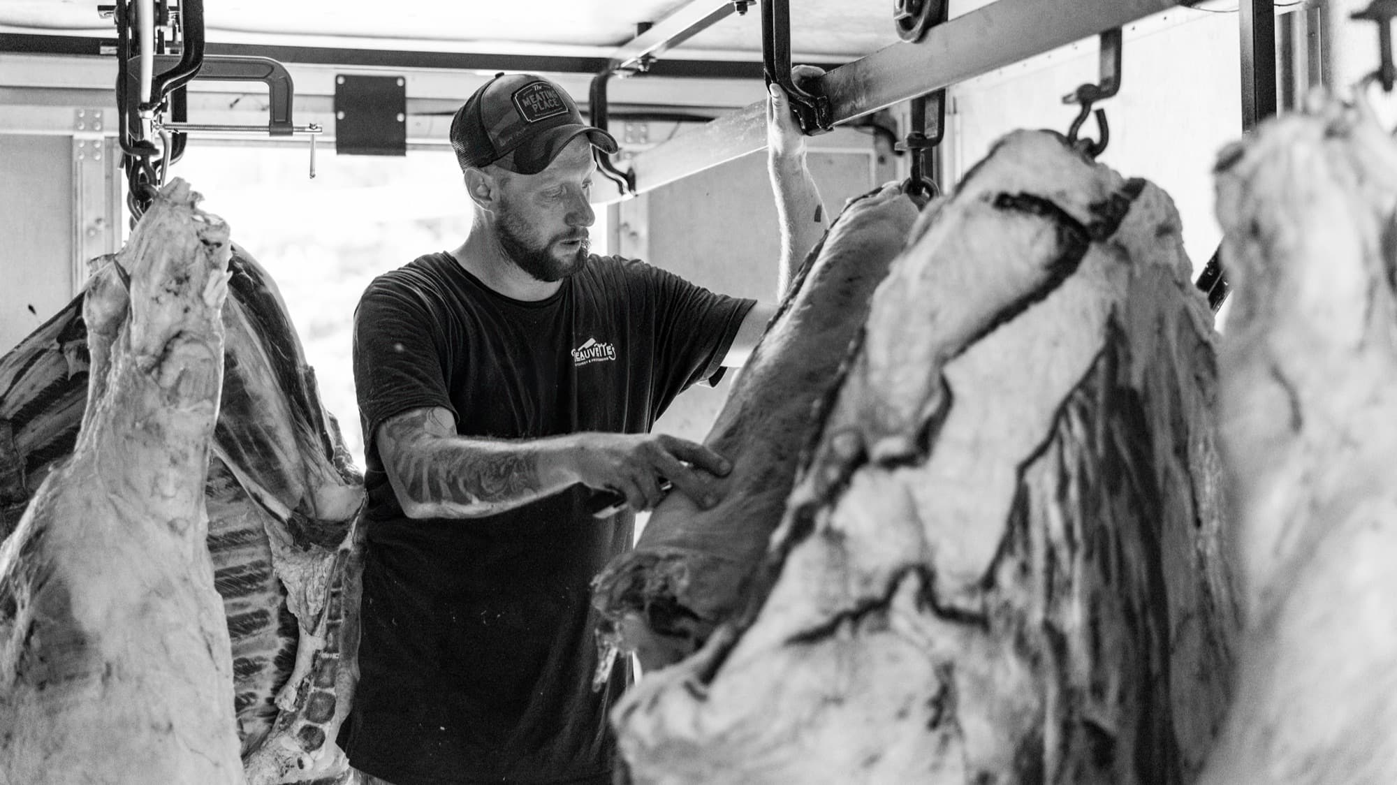A Beauvette's butcher working among hanging beef in the cooler